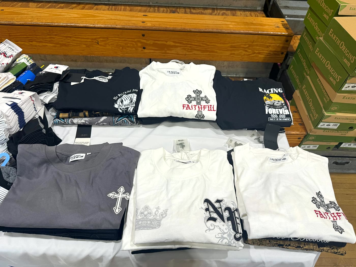 Folded new T-shirts and packs of socks laid out on a table.